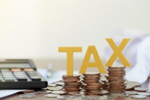 A conceptual photo of coins and the word TAX, illustrating the Spanish wealth tax for UK residents.